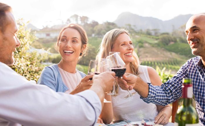 Happy friends raising their glasses in a toast at a winery